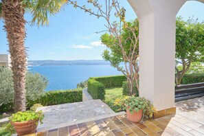 Una terraza con suelo de piedra, una palmera y vista al mar.