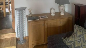 A living room with a wooden cabinet, a framed collage on the wall, a floor lamp, and a sofa. - Minimum Stay two Nights (Larne)