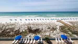 A beach view with a wooden boardwalk, beach umbrellas, and lounge chairs. - IBR 5006: Ocean Star - Catch the Breeze and Feel the Peace! (Fort Walton Beach)