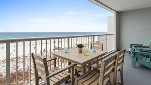A balcony with a table and chairs overlooking a beach. - IBR 5006: Ocean Star - Catch the Breeze and Feel the Peace! (Fort Walton Beach)