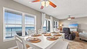 A dining area with a white table, chairs, and a ceiling fan. - IBR 5006: Ocean Star - Catch the Breeze and Feel the Peace! (Fort Walton Beach)