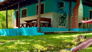 A single-story house with a tiled roof, a wooden deck, and a green exterior wall.