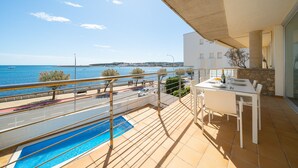 Un balcon avec une piscine, une table à manger et une vue sur la mer.