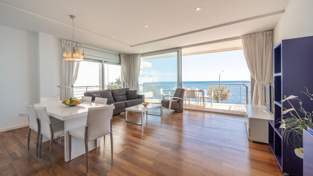 Un salon moderne avec un coin repas, de grandes fenêtres et une vue sur la mer.