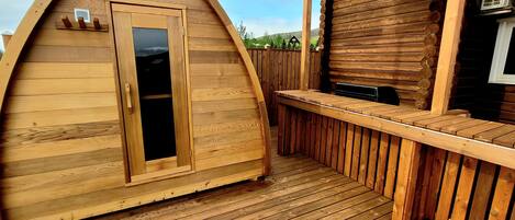 A wooden deck with a small wooden structure featuring a door and a bench.