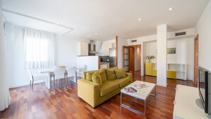 Uma sala de estar moderna com sofá, mesa de centro e área de jantar.