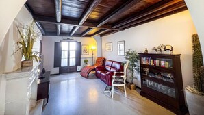 A spacious living room with a red leather sofa, a white armchair, and a bookshelf. - Housing of Charme With Rooftops Balconies (Galatone)