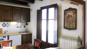 A kitchen with wooden cabinets, a sink, and a dining area with a table and chairs. - Housing of Charme With Rooftops Balconies (Galatone)