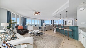 A spacious living room with a sofa, coffee table, and a dining area with a bar. - Oceania 5, New Owner, Impeccable Beachfront Condo!! (Gulf Shores)