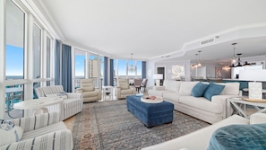 A spacious living room with a large window, a dining area, and a kitchen. - Oceania 5, New Owner, Impeccable Beachfront Condo!! (Gulf Shores)