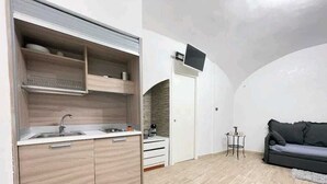 Una cocina compacta con horno integrado, un lavamanos y un pequeño comedor con mesa y sillas.