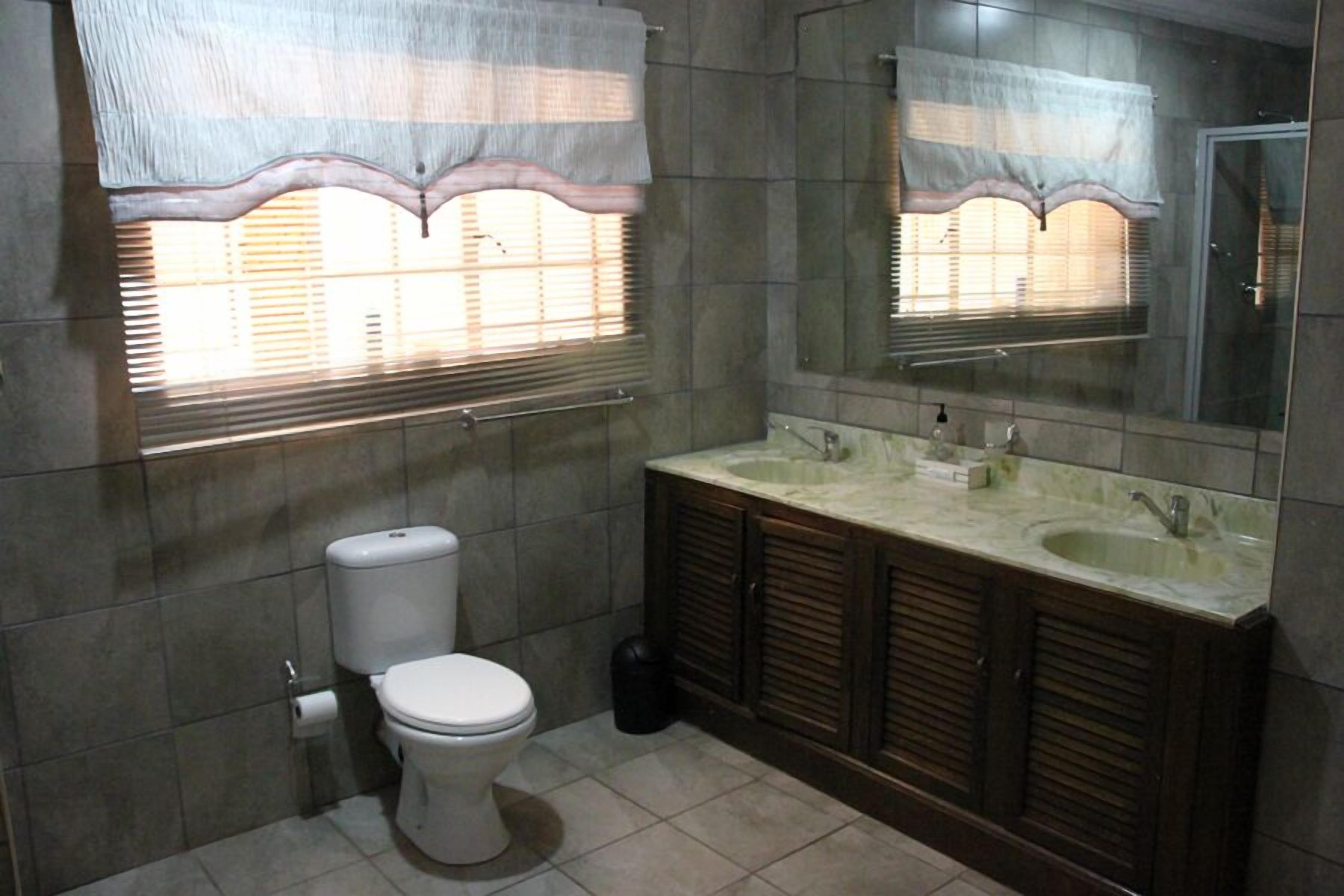 Un baño con inodoro, lavamanos y espejo.