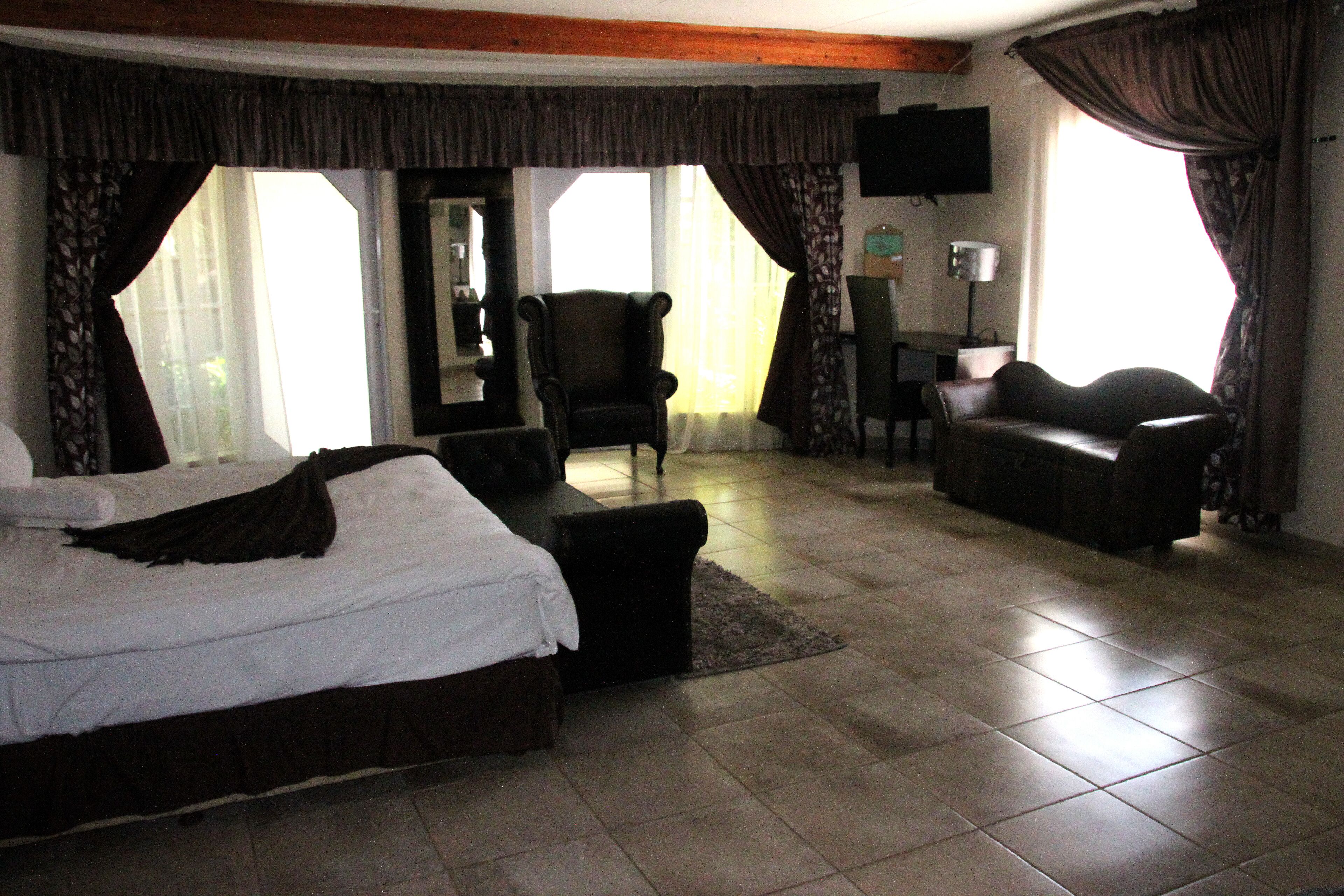 Una habitación de hotel con cama, sofá, sillón y escritorio.