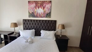 Een hotelkamer met een groot bed, twee nachtkastjes met lampen, een bureau en een stoel.