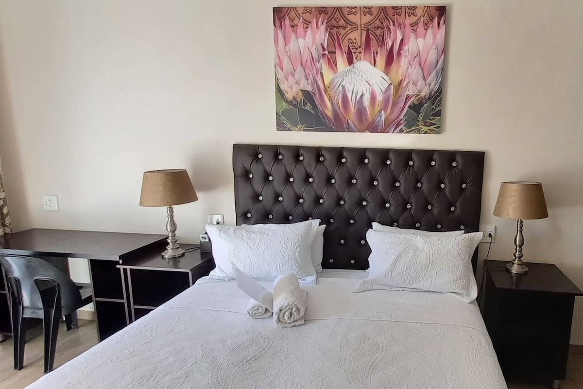 Een hotelkamer met een groot bed, twee nachtkastjes met lampen, een bureau en een stoel.