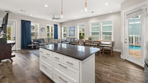 A spacious living area with a central island, a dining table, and a view of a pool.