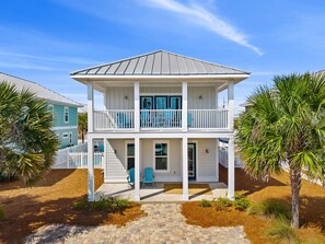 A two-story house with a covered porch and a fenced yard.
