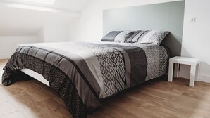 A modern bedroom with a large bed, patterned bedding, a small white nightstand, and a skylight.