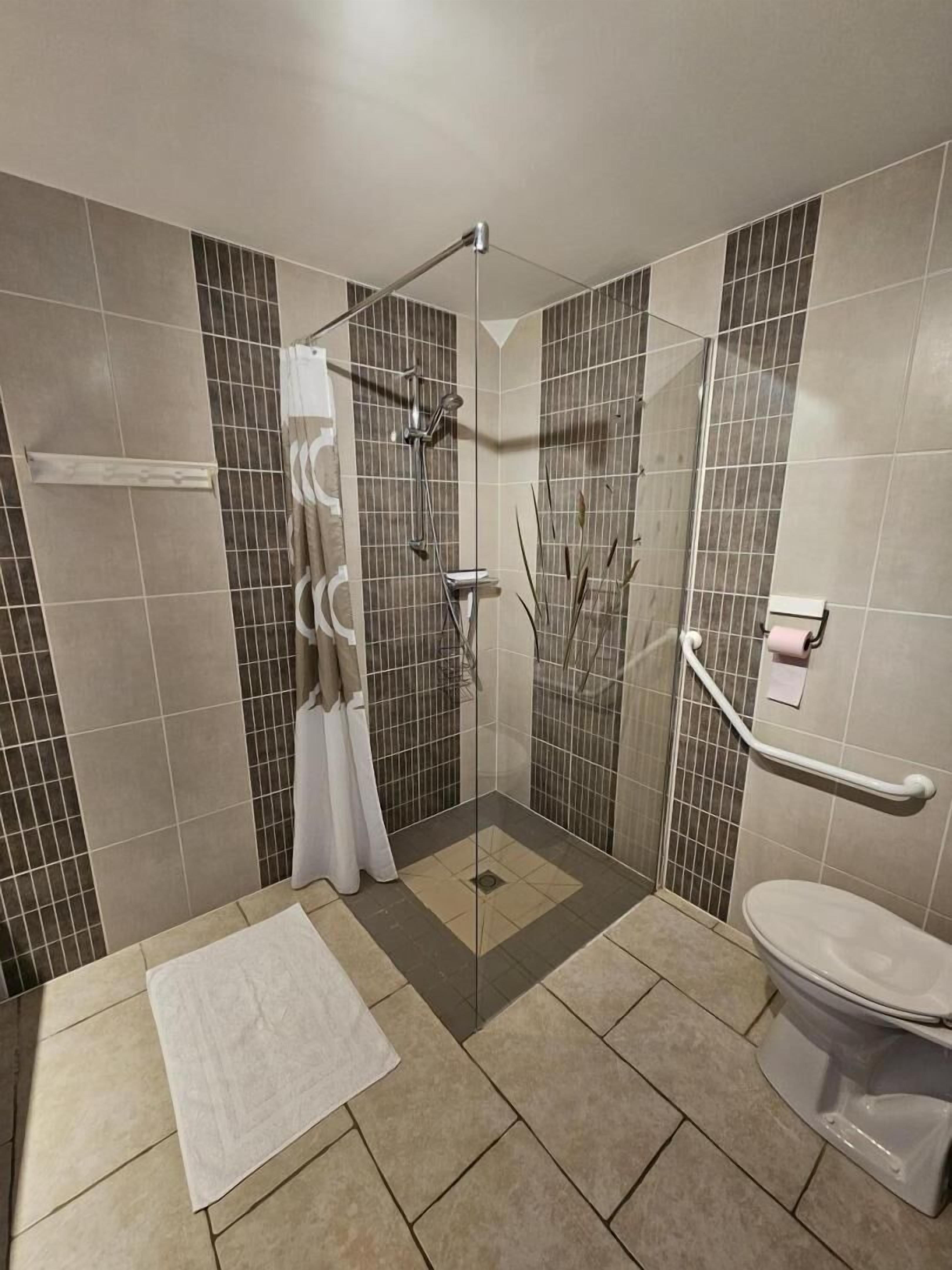 Une salle de bain avec une douche, des toilettes et une serviette blanche sur le sol.