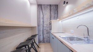 A modern kitchen with a marble backsplash, a stainless steel sink, and black bar stools.