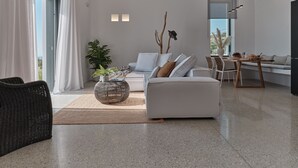 Una sala moderna con un sofá blanco, una mesa de centro y una zona de comedor con una mesa dispuesta para dos.