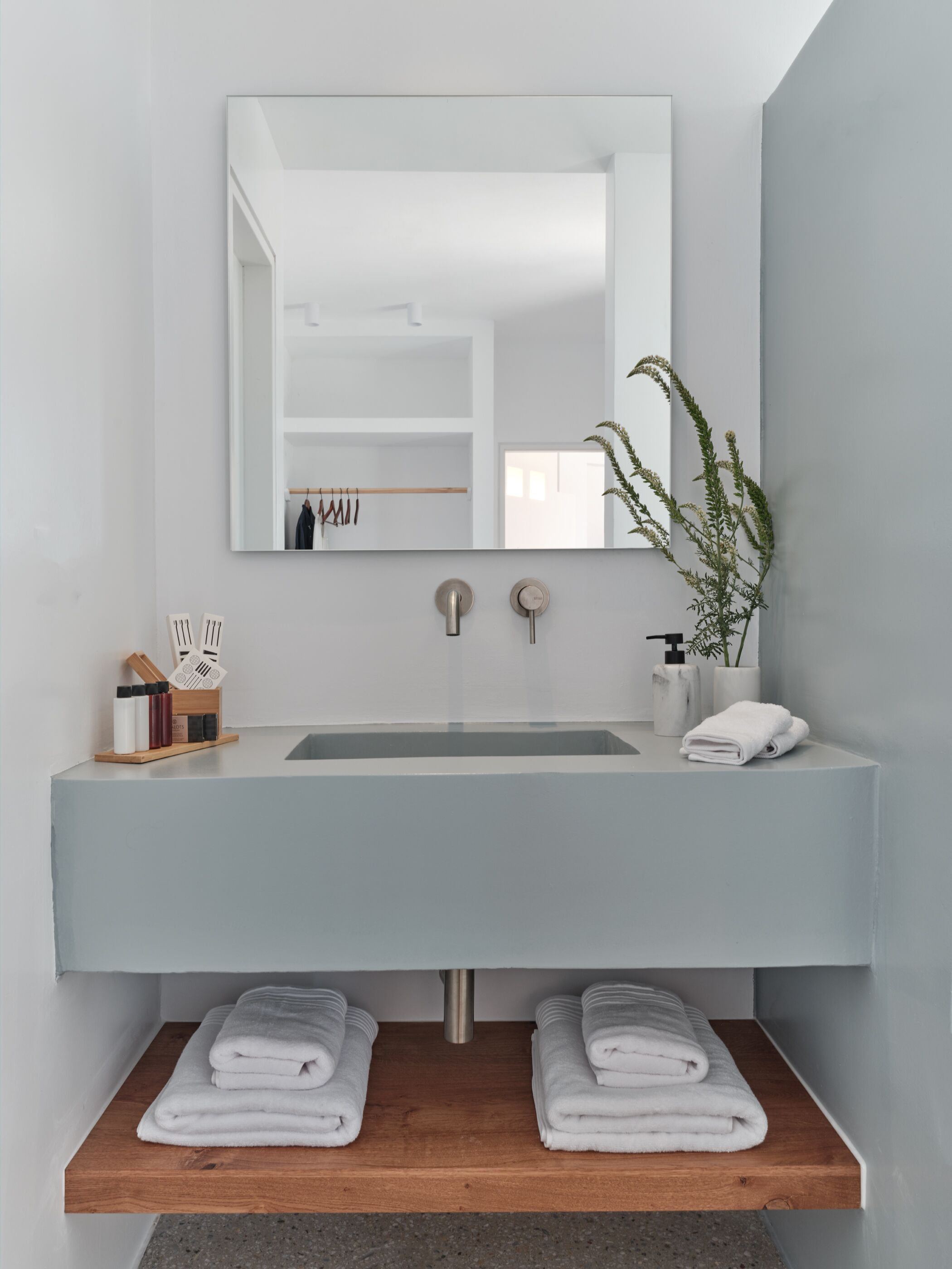 Un baño moderno con un espejo grande, un lavamanos y dos toalleros.