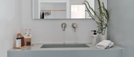 Un baño moderno con un espejo grande, un lavamanos y dos toalleros.