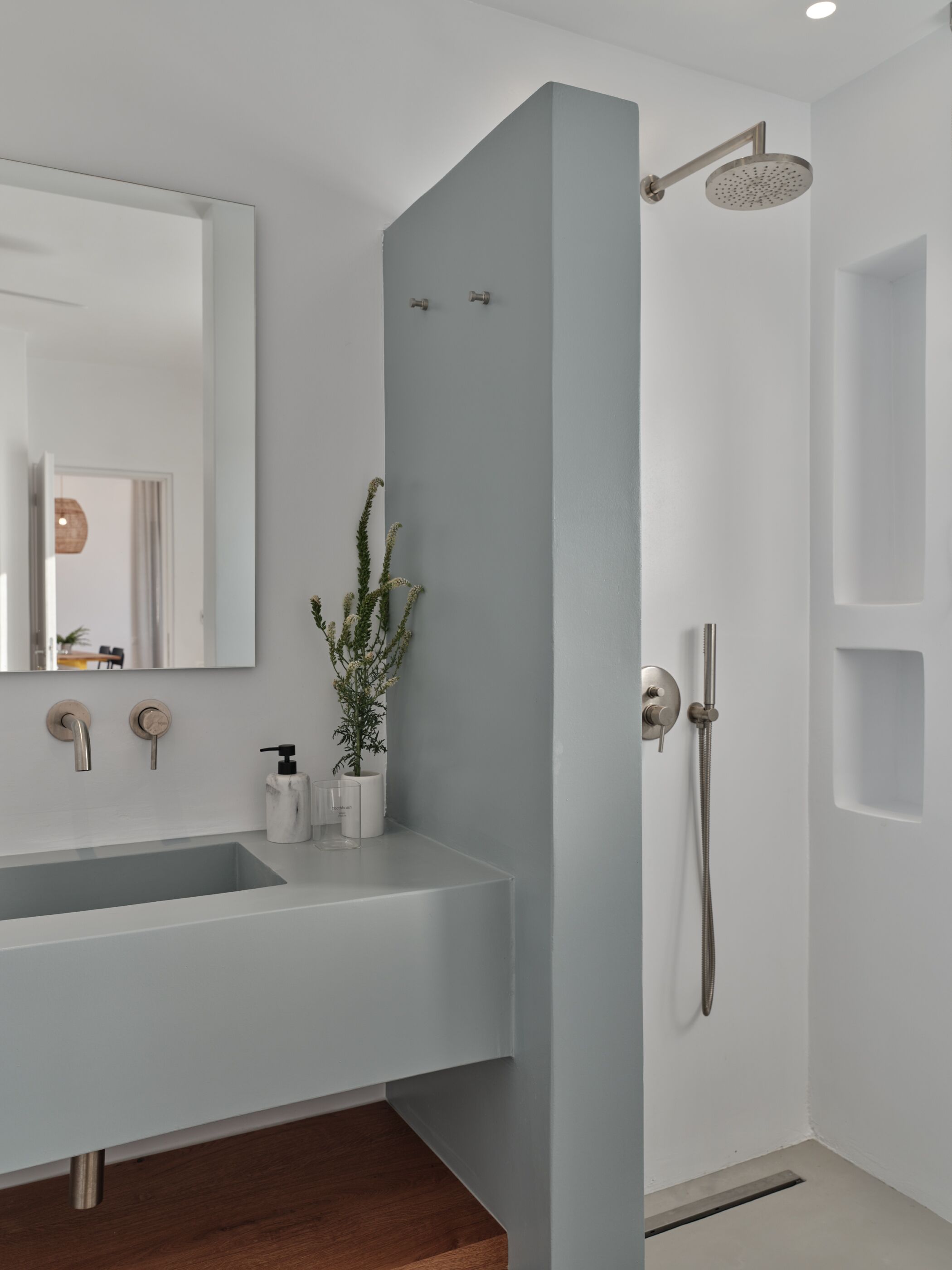 Een moderne badkamer met een groot wastafel, een spiegel, een douche en een potplant.