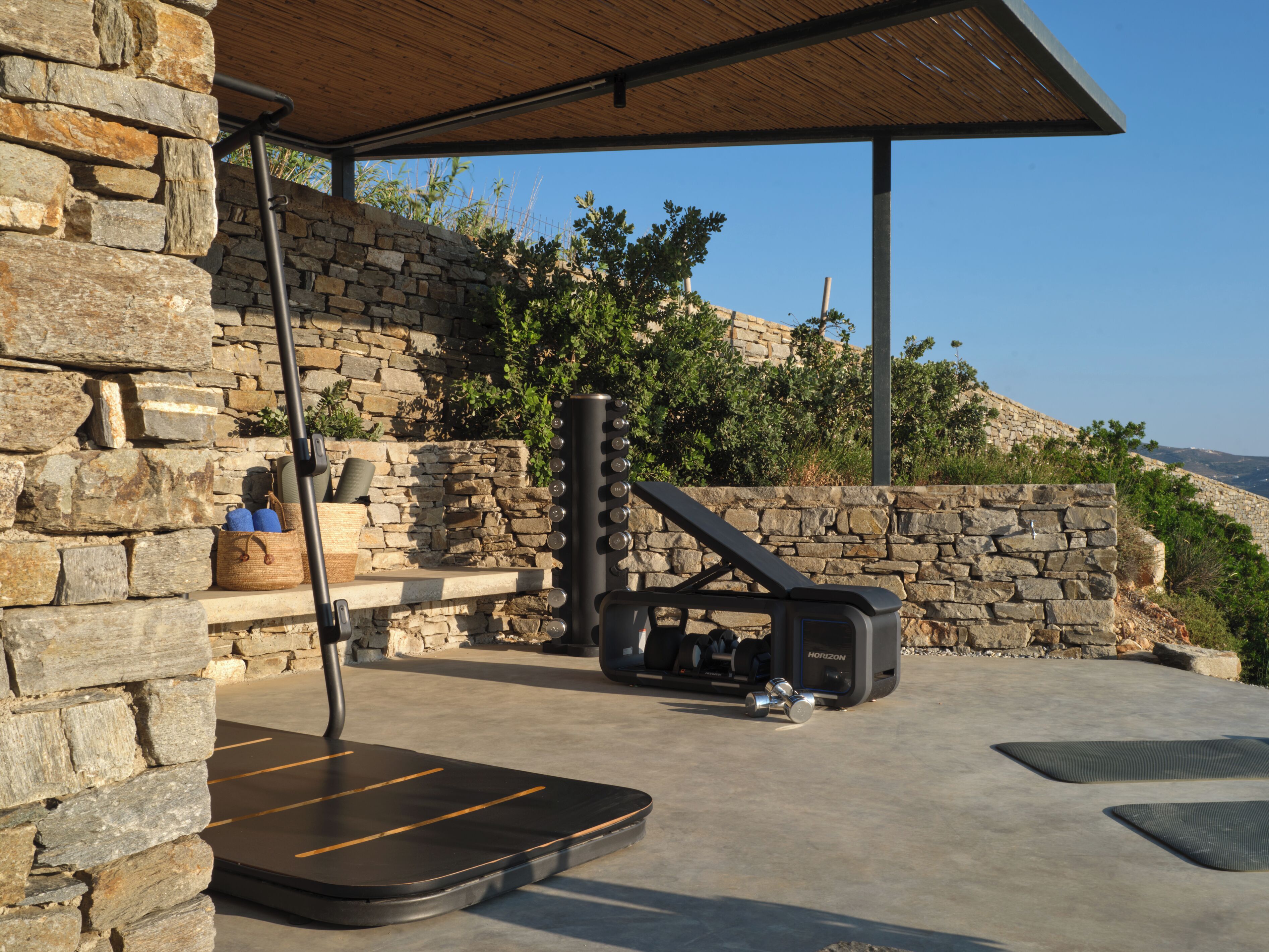 A stone wall, a covered outdoor area with a stone bench, and a sauna.