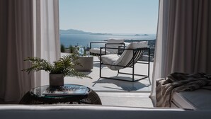 A balcony with a view of the sea, a chair, a table with a plant, and a sofa. - Olithos Villas (Paros)