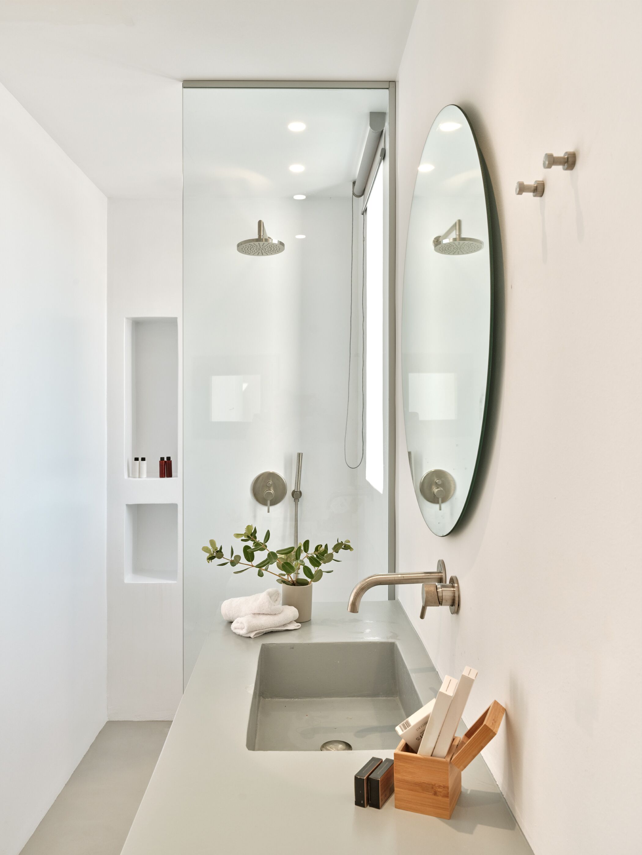 A modern bathroom with a large mirror, a shower, and a sink with toiletries.