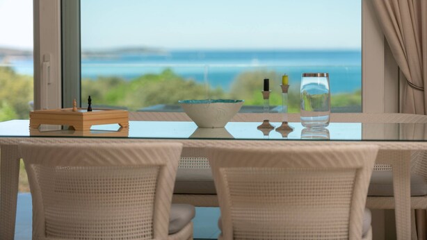 Ett matbord med utsikt över havet, en skål och ett glas vatten.