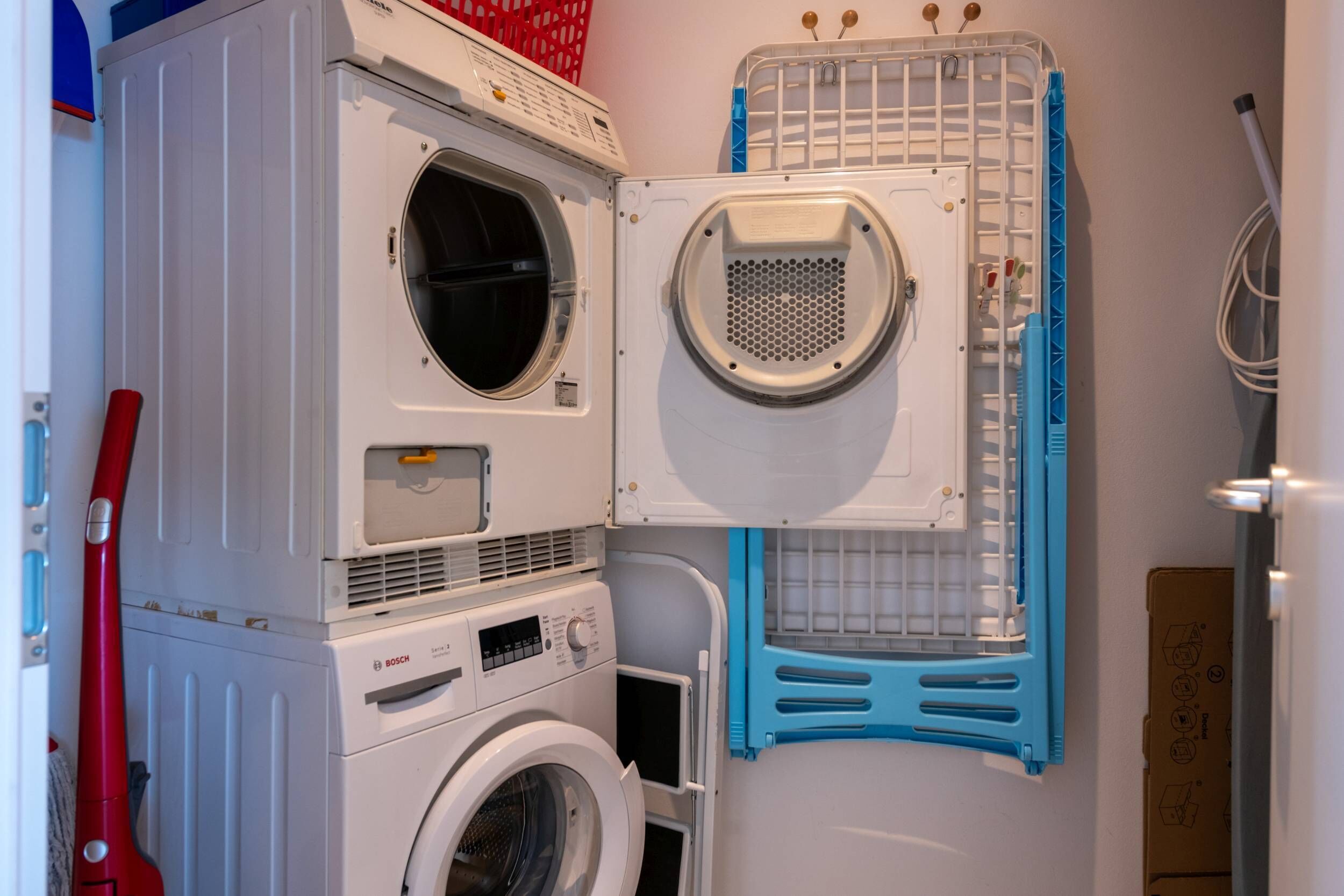 A compact laundry area with stacked washing machines and a drying rack.