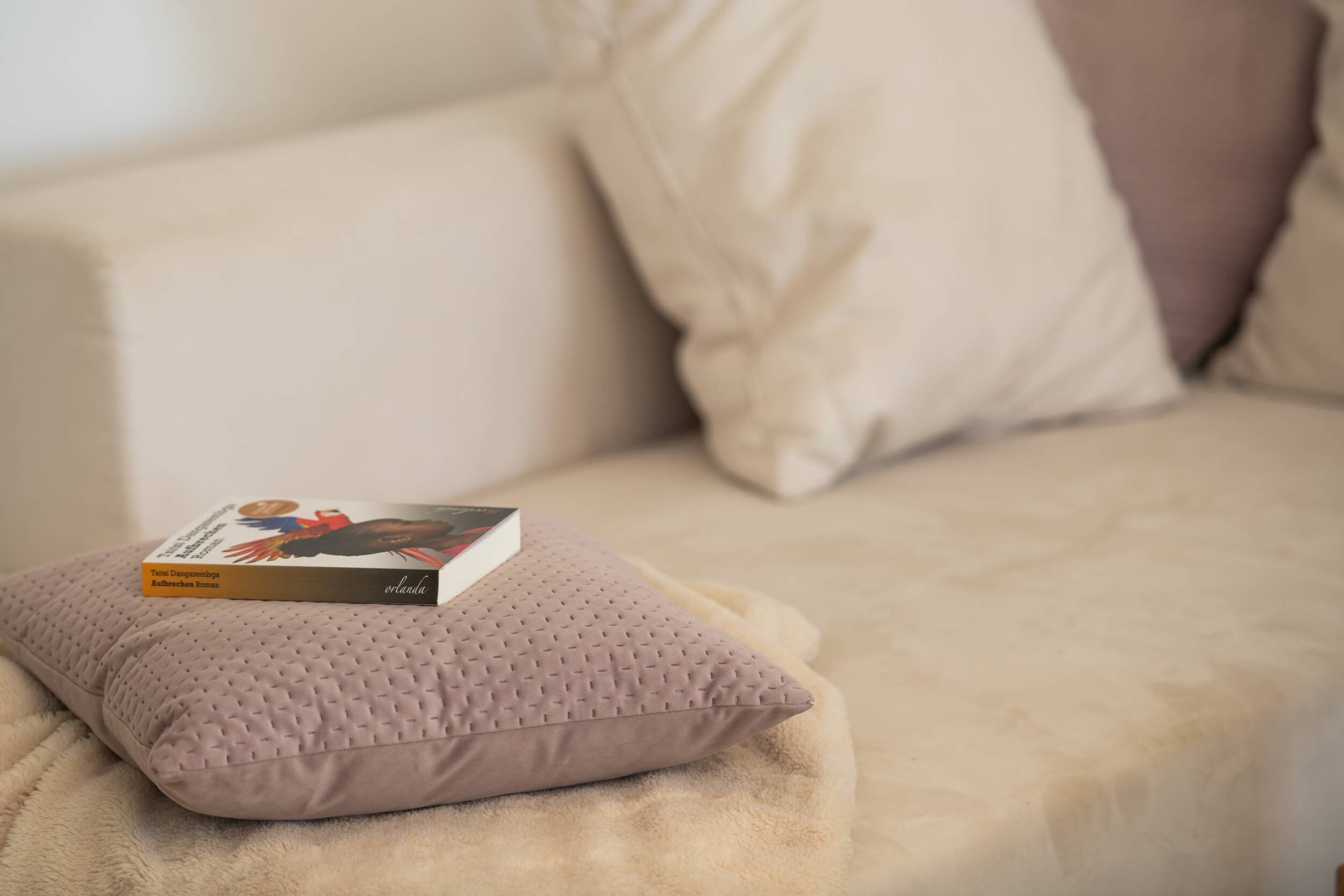 En beige sofa med en struktureret pude og en bog med titlen "Time Management for Freelance Writers".