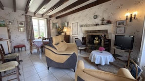 Ein Wohnzimmer mit Kamin, Fernseher und Essbereich mit Tisch und Stühlen.