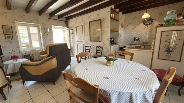 A dining area with a round table, chairs, and a vase of flowers.