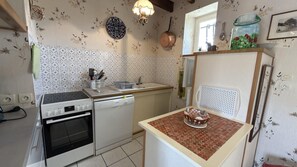 Eine Küche mit Herd, Backofen, Spüle und einem kleinen Tisch mit einem dekorativen Gegenstand.