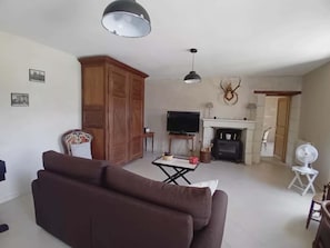 Una sala de estar con sofá, televisor, chimenea y mueble de madera.