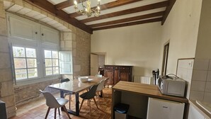 A kitchen with a wooden table, chairs, a refrigerator, and a microwave.