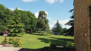 A paved pathway leading to a building with a brick facade, surrounded by a well-maintained grassy area with trees.