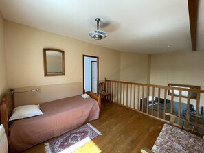 A bedroom with a single bed, a wooden headboard, a mirror, and a ceiling fan. - Le Petit Ru - Lizant (LIZANT)
