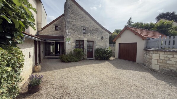 A stone building with a gravel driveway, a wooden door, and a garage.