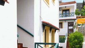 Un edificio blanco con escaleras de tejas rojas y barandilla verde.