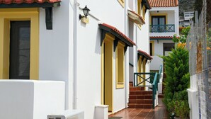 Una calle estrecha con edificios blancos, puertas amarillas y tejados de tejas rojas.