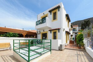 A two-story building with a balcony, a wooden bench, and a tiled patio area. - Elen-Mari (Hersonissos)