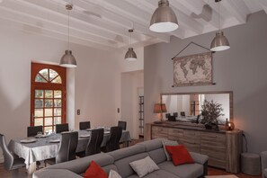 A dining area with a table set for six, a sofa with cushions, and pendant lighting. - La Charmille - Saint-gaudent (SAINT-GAUDENT)