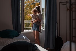 A hotel room with a bed, a window with curtains, and a view of trees outside. - La Charmille - Saint-gaudent (SAINT-GAUDENT)