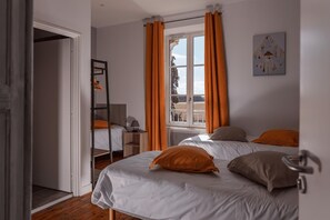A bedroom with two beds, a window with curtains, a bedside table, and a bunk bed in the corner. - La Charmille - Saint-gaudent (SAINT-GAUDENT)