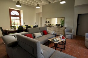 A living room with a sofa, armchairs, a coffee table, and a dining area with chairs and a table.