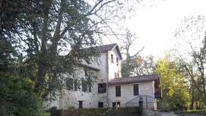 A historic stone building with a water feature in front, surrounded by trees. - Le Moulin de L'anglée (SANXAY)